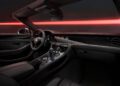 Discover the allure of the Bentley's Black Edition. The luxury car interior boasts black leather seats, a multi-function steering wheel, and a sophisticated dashboard with various dials. Red ambient lighting enhances the sleek design, echoing the elegance of Continental & Flying Spur craftsmanship.