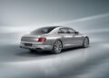 The Bentley Continental GT is a sleek silver luxury sedan, boasting 671HP, elegantly poised on a glossy surface. Viewed from the rear and side, it exudes power and sophistication against a gradient gray background.