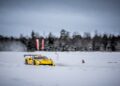 A yellow Ferrari race car on a snow-covered track speeds past blurred trees, embodying the spirit of the Purosangue.