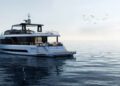 A modern white Arcadia Yachts A80new floats on calm, open water under a clear sky, with a flock of birds flying in the distance—an elegant vision of luxury and sustainability at sea.