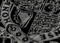 Close-up of an intricately embroidered design featuring a harp and coats of arms on a dark fabric background, symbolizing elegance worthy of a Royal Warrant.