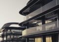 Modern buildings with curved glass facades and dark structural elements, featuring multiple floors and balconies under soft, natural light—an exquisite example of luxury real estate inspired by the elegance of BRABUS Island in Abu Dhabi.