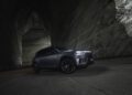 A dark-colored BRABUS SUV parked inside a large, cavernous space with textured walls. Dim lighting highlights the vehicle's contours and wheels, showcasing its 637HP prowess.