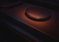 In a dim red-orange glow, the close-up of a Sennheiser speaker evokes the sleek precision of a BRABUS-tuned smart Car, combining power and elegance in harmonious design.