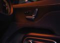 The interior of the BRABUS car door boasts illuminated control buttons and a speaker, enhanced by ambient orange lighting and a textured panel, all within the prestigious realm of a smart Car experience.