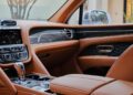 Experience the bespoke luxury of a Bentley interior, where tan leather seats and chrome accents harmonize with a sleek digital display and gearshift knob.