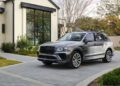 A Bentley Bentayga sits elegantly on a stone driveway, complementing the modern house with its expansive windows and manicured lawn.
