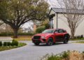 A bespoke Bentley Bentayga SUV is elegantly parked on a paved driveway beside a modern house, framed by large trees and a beautifully landscaped garden.