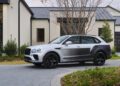 A sleek silver and black Bentley SUV is artfully parked in front of a modern house with expansive windows and a dark roof, reflecting the elegance of bespoke Bentaygas.