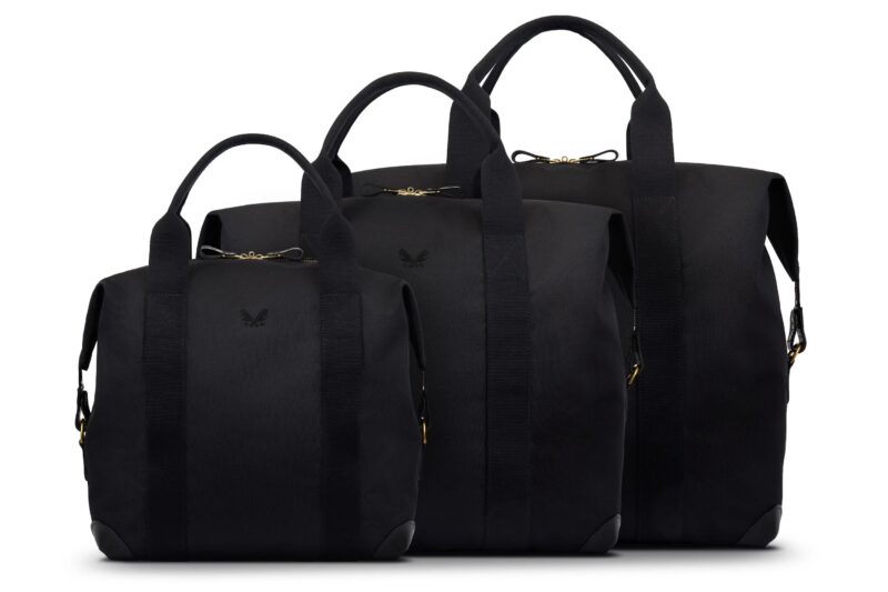 Three black tote bags of different sizes are displayed side by side against a white background. Each bag, perfect for a style upgrade, features two top handles and subtle embossed logos on the front.