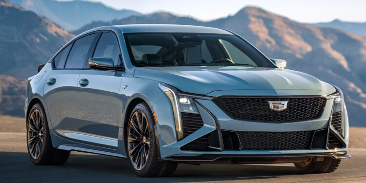 A silver Cadillac CT5-V Blackwing sedan with 668HP is parked on a paved surface with mountains in the background under clear skies.