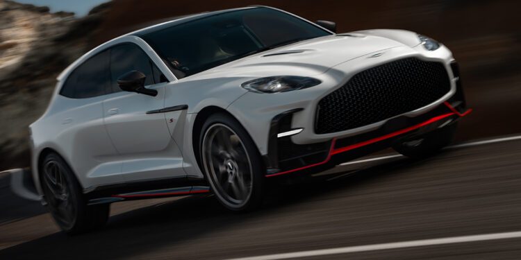 A white Aston Martin DBX S Super-SUV with black and red accents is driving at speed on a curved mountain road.