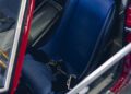 Close-up view of a blue bucket seat with black harness inside a red Ferrari 330 LM/250 GTO, seen through the open driver's side door at Cavallino Classic 2025.