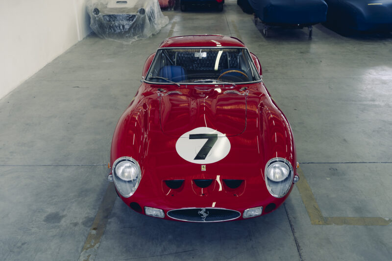 A red vintage Ferrari 330 LM/250 GTO with the number 7 on the hood is parked in an indoor garage space, ready to impress at the 2025 Cavallino Classic.