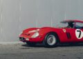 A classic red Ferrari 250 GTO with the number 7 on the door is parked on pavement in front of a gray wall, reminiscent of a scene from the Cavallino Classic.