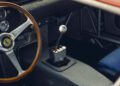 Close-up of a classic Ferrari 330 LM/250 GTO interior shows a wooden steering wheel with Ferrari logo, metal gear shift, dashboard gauges, and part of a blue seat—captured at the 2025 Cavallino Classic.