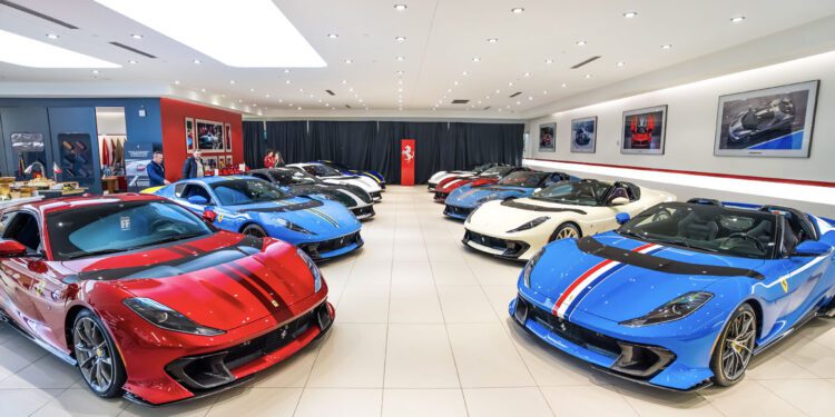 A showroom featuring an exhibition of luxury sports cars, including the stunning Ferrari 812 Competizione in red, blue, and white. The well-lit room boasts framed photos on the walls, enhancing the elegant atmosphere.