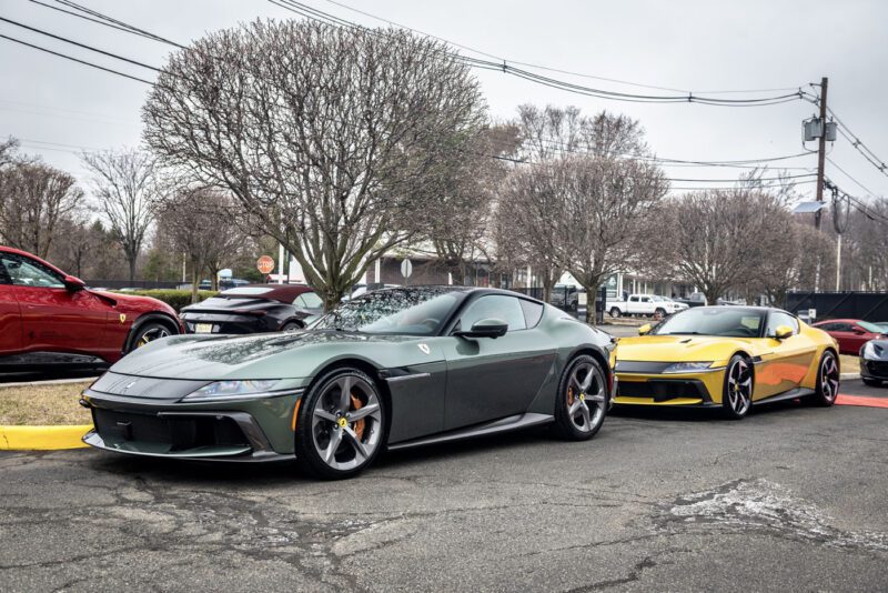 Two sleek sports cars, a green and a yellow, are parked on the street. Against the backdrop of leafless trees and an overcast sky, the scene feels like an impromptu Ferrari 812 Competizione exhibition.