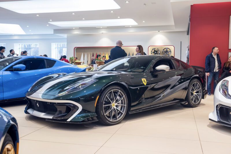 The Ferrari 812 Competizione steals the spotlight at the Exhibition in Central New Jersey, a sleek black sports car dazzling the crowd amidst an array of vehicles in the showroom.