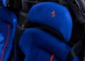 Close-up of a Ferrari's seat interior in Beverly Hills, featuring blue upholstery with a red embroidered prancing horse logo on the headrest, reminiscent of the Daytona SP3's luxurious design, and blue seat with orange accents.
