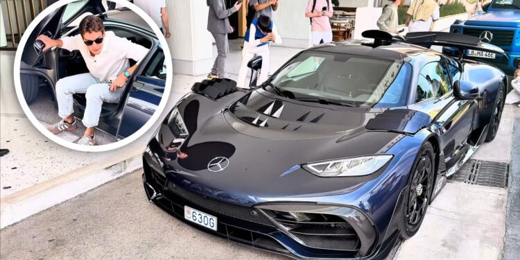 A man exits a car as people gather to take photos of a parked blue Mercedes-AMG One sports car on the street in Monaco, possibly hoping to spot George Russell nearby.