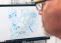 Person analyzing a computer screen displaying abstract shapes and patterns in blue and white tones.