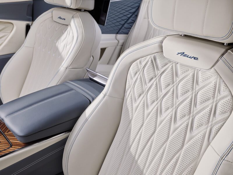 Close-up of a Bentley's interior revealing exquisite white quilted leather seats with "Azure" embroidered, and a blue leather armrest crafted to perfection. Experience the fusion of luxury and style with every detail designed as if guided by AI precision.