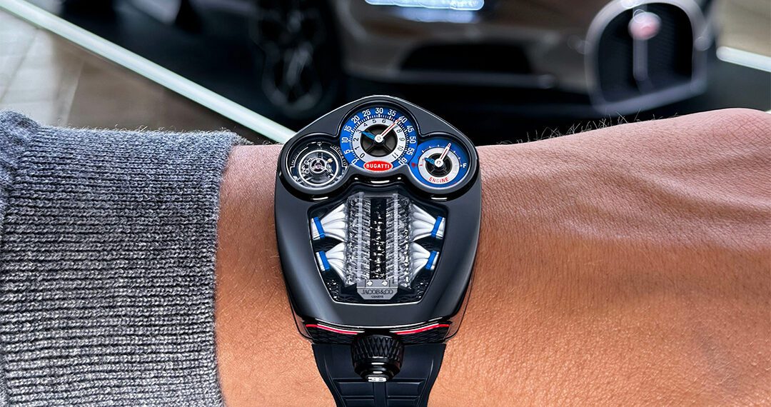 A close-up of a person’s wrist wearing a futuristic Jacob & Co. Bugatti Tourbillon watch, inspired by automotive design, with a luxury sports car blurred in the background.