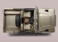 Top-down view of a beige Jeep with two tan seats, open roof, visible dashboard, and a spare tire mounted in the cargo area—evoking classic Land Rover style with Defender Soft Top vibes.