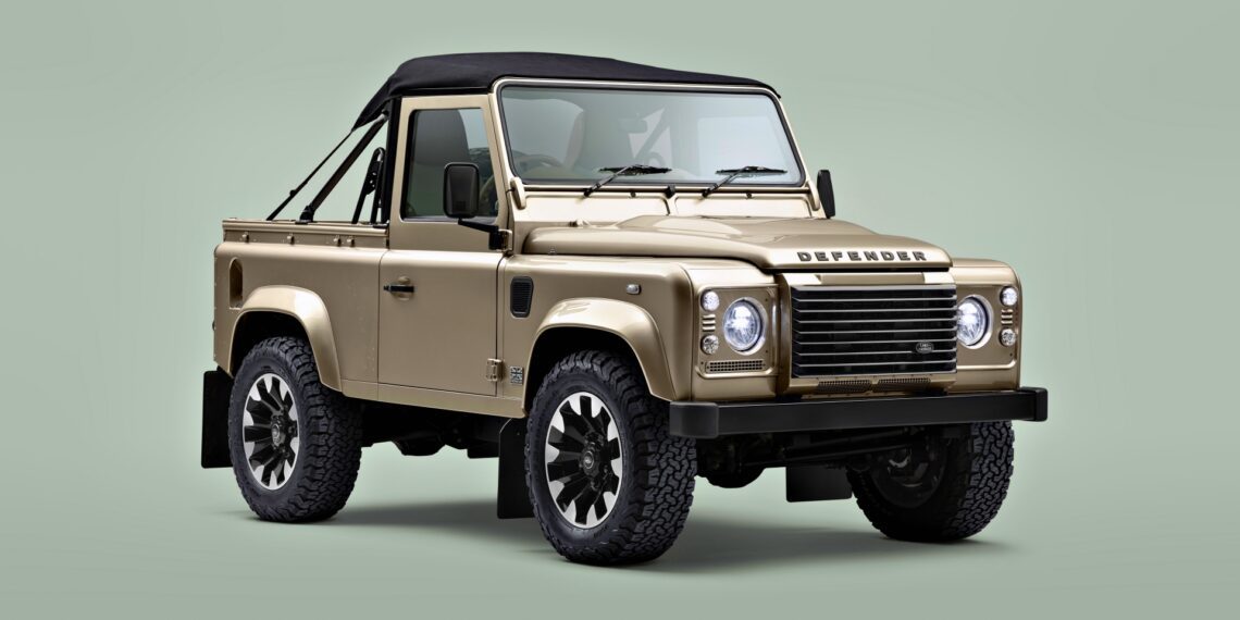 A beige Land Rover Defender Soft Top with a black roof is parked on a light green background, facing slightly left.