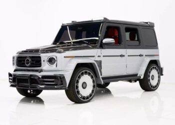 A white and black Mercedes-AMG G-Wagon with tinted windows and large custom wheels is parked in a white studio setting, showcasing the bold presence of this iconic luxury SUV.