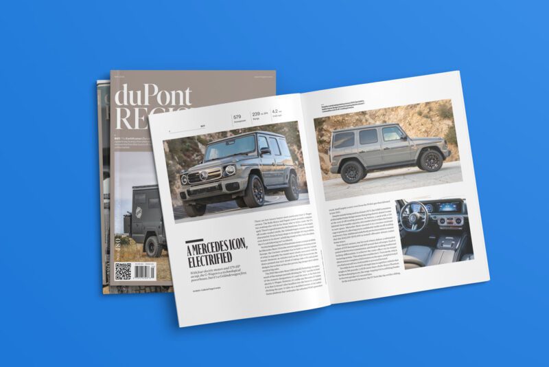 The May 2025 issue of duPont REGISTRY, No. 480, lies open on a blue surface, spotlighting a Mercedes SUV alongside captivating articles and images. A second magazine peeks from beneath it, hinting at even more discoveries within its pages.