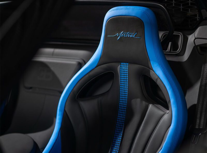 Close-up of a blue and black leather car seat, styled in French Racing Blue, with "Mistral" embroidered on the headrest. This Bugatti Mistral seat features a houndstooth pattern on the center panel.
