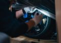 A person with gloves carefully unveils a Bugatti Mistral wheel in the iconic French Racing Blue, nestled inside a box at Miller Motorcars.