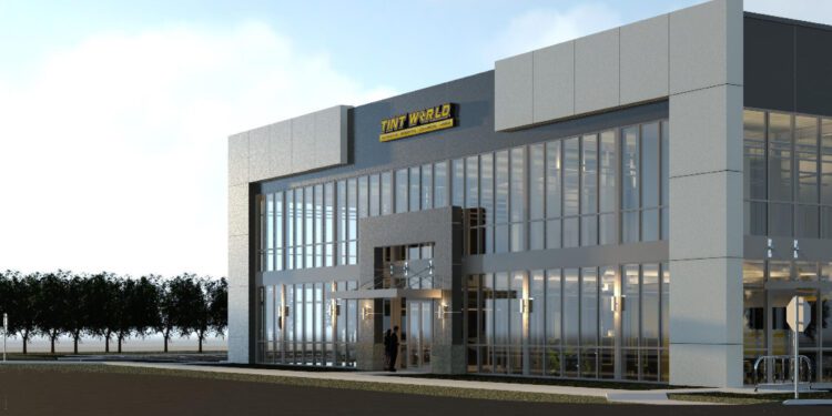 A modern two-story building with large glass windows and a sign reading "TNT World" on the front, reminiscent of an automotive styling center, is surrounded by a few trees and set against a clear Florida sky.