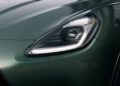 Close-up view of a 2025 Maserati Grecale’s left headlight and part of the hood, featuring metallic green paint and sleek, angular design lines.