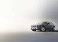 A gray luxury sedan, reminiscent of the Goodwood Era, is parked on a smooth gradient floor with a light background, echoing the elegance typical of Rolls-Royce concept cars.