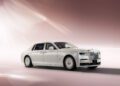 A white luxury Phantom sedan, reminiscent of a Rolls-Royce, sits elegantly parked in a well-lit, neutral-toned space.