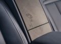 Close-up of a Cullinan Daisy's rear seat armrest, a one-off detail featuring light-colored wood trim with a flower engraved design, surrounded by grey perforated leather upholstery.