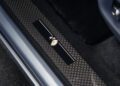 Close-up of a Rolls-Royce Cullinan Daisy door sill with a checkered pattern and a black plate featuring a white and yellow daisy graphic, highlighting this unique one-off detail.
