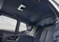 The interior of this Rolls-Royce Cullinan features black leather seats, rear-seat entertainment controls, and a star-patterned ceiling light display.