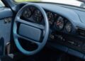 Close-up of a 1987 Porsche 959 Speedster’s blue interior in Milan, showing the steering wheel, dashboard with analog gauges, and control switches—offered by RM Sotheby's.