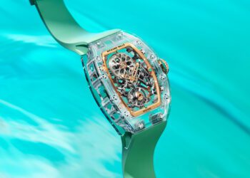 A close-up of a transparent Richard Mille RM 75-01 mechanical wristwatch with a green strap, floating above a turquoise water background—part of the stunning Sapphire Collection.