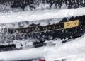 Close-up of the rear of a black car covered in snow and ice, with a yellow "PROTOTYPE VEHICLE PTV" label, captured during cold weather testing in Sweden for the Range Rover Electric.
