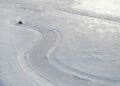 A Range Rover Electric navigates a winding road through a snow-covered, frozen landscape in Sweden, its tracks curving through the ice during cold weather testing.