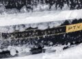 A close-up of a black Range Rover Electric prototype vehicle partially covered in ice, displaying a label that reads "PROTOTYPE VEHICLE PTV" in yellow text, hinting at its advanced 300 mile range electric SUV capabilities.