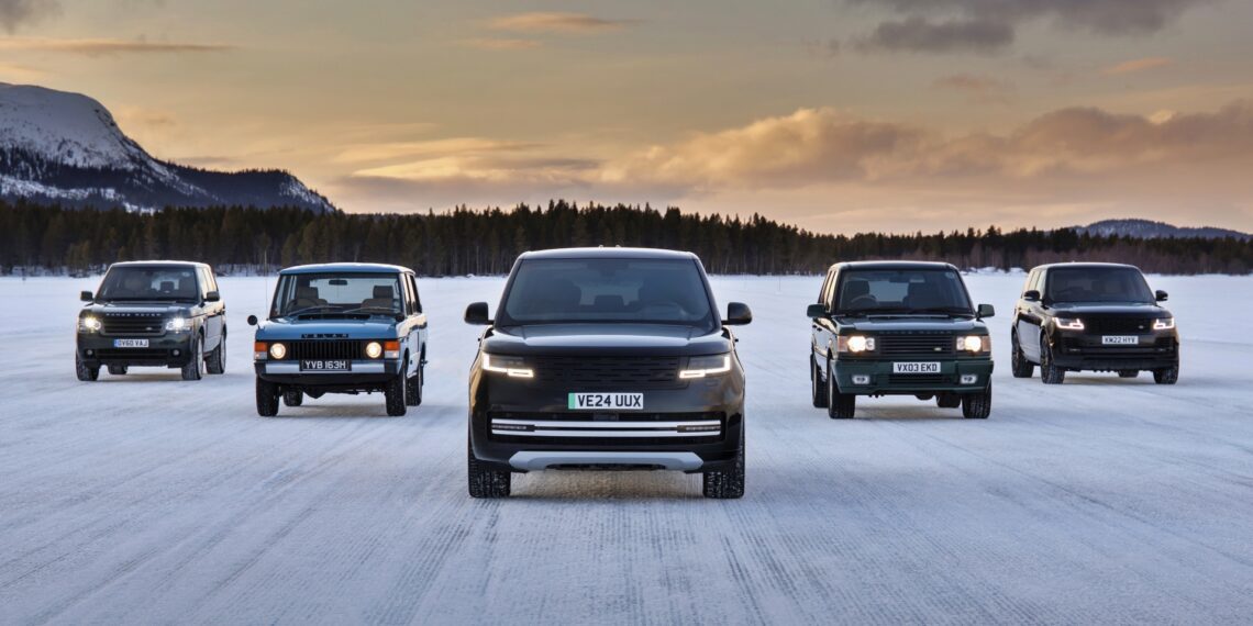 Five Land Rover SUVs of different generations, including the upcoming Range Rover Electric with a 300 mile range, are parked side by side on a snowy landscape at sunset, with mountains and trees in the background.