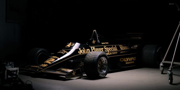 Black and gold Formula 1 car with "John Player Special" on the side, parked in a dimly lit garage.