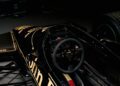 Interior view of a classic black and gold racing car cockpit, featuring a steering wheel with "Momo" branding and various dials and controls, with racing seats visible.