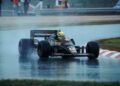 A race car speeds through a wet track under rainy skies, with sponsor logos shimmering on the body. Inside, a helmeted driver channels Ayrton Senna's legendary spirit, striving for that coveted F1 victory.